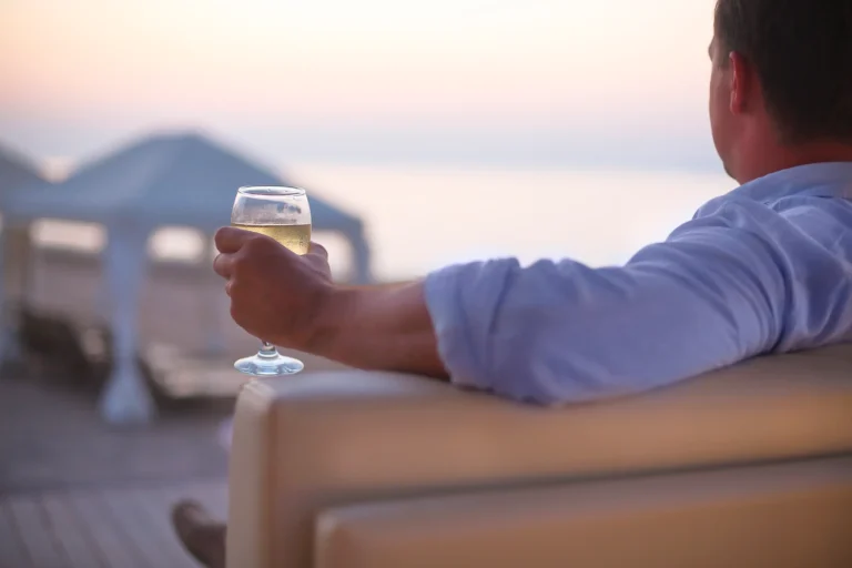 relaxing man with glass of white wine on the beach