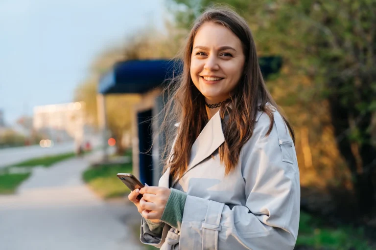beautiful smiling girl with long hair in a grey trench coat