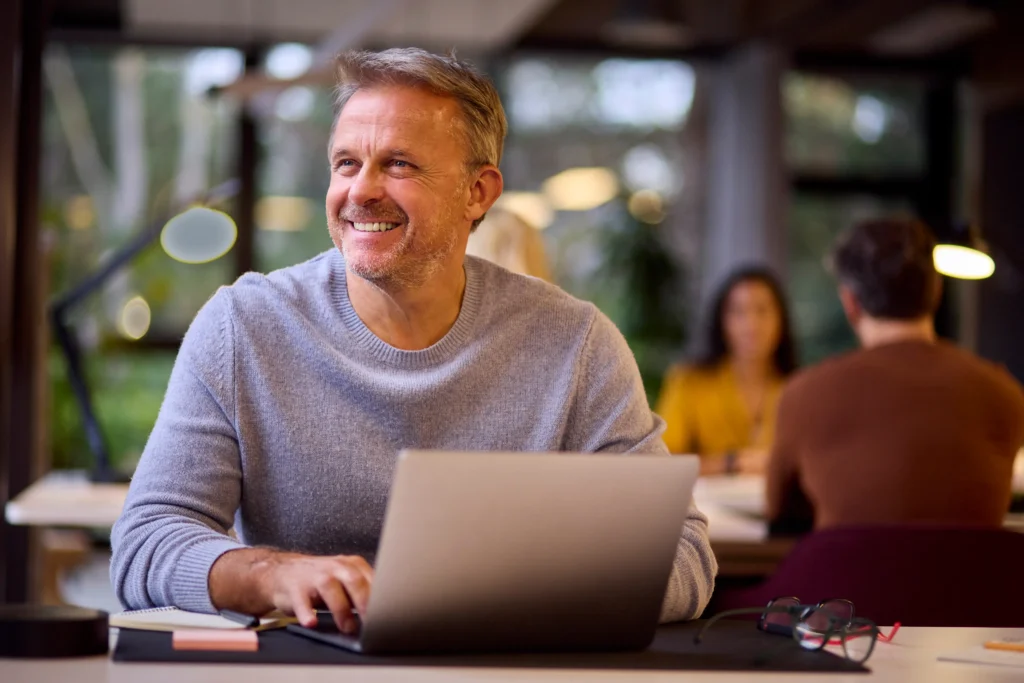 Leende vuxen affärsman som jobbar med hemsidor för företag